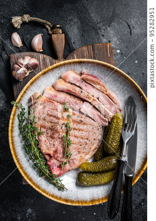 Barbecue dinner - Pork steaks from neck meat in plate with hebs. Black background. Top view 95282951