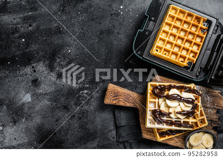 Breakfast with Belgian waffles, banana and Chocolate Syrup. Black background. Top view. Copy space 95282958