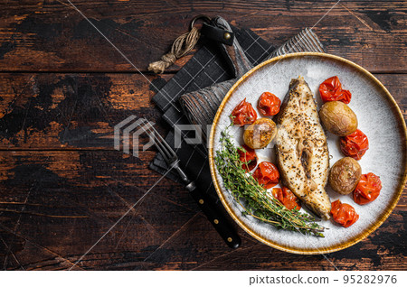 Grilled halibut fish steaks with tomato and potato in plate. Wooden background. Top view. Copy space Grilled halibut fish steaks with tomato and potato in plate. Wooden background. Top view. Copy space 95282976