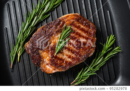 Roasted rib eye steak, ribeye beef meat in a grill pan. Black background. top view 95282978