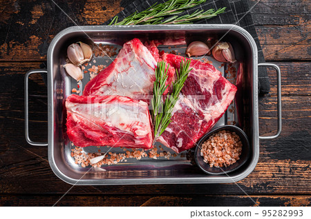 Raw beef Short Ribs in steel tray with rosemary. Wooden background. Top view 95282993