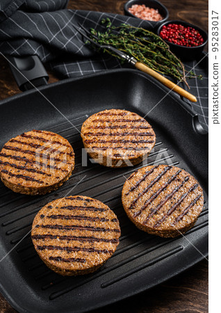 Grilled Vegetarian plant based meat burger patties, vegan cutlets on grill skillet. Wooden background. Top view 95283017
