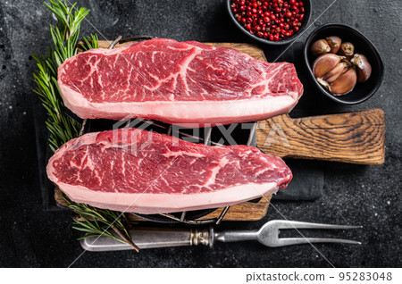 Raw top sirloin beef meat steak or brazilian Picanha on grill. Black background. Top view 95283048