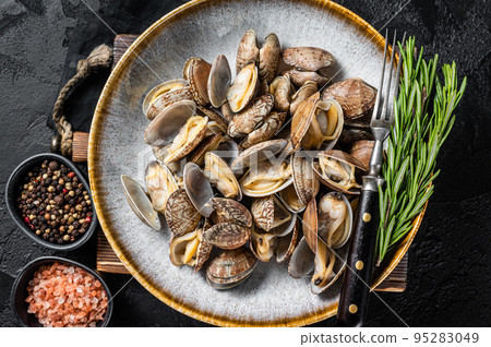 Steamed cooked shells Clams vongole in a plate with herbs. Black background. Top view 95283049