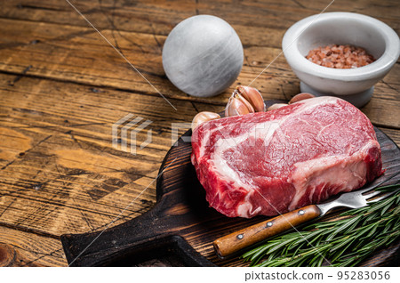 Raw Rib eye Steak, ribeye beef meat on wooden board with thyme. Wooden background. Top view. Copy space Raw Rib eye Steak, ribeye beef meat on wooden board with thyme. Wooden background. Top view. Copy space 95283056