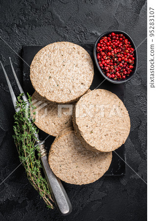 Uncooked Burgers cutlets made from plant based meat, raw vegan patties. Black background. Top view Uncooked Burgers cutlets made from plant based meat, raw vegan patties. Black background. Top view 95283107