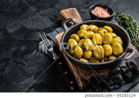 BBQ Grilled olives with garlic, olive oil and spices. Black background. Top view. Copy space 95283124
