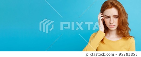 Headshot Portrait of tender redhead teenage girl with serious expression looking at camera. Caucasian woman model with ginger hair posing indoors.Pastel blue background. Copy Space. Headshot Portrait of tender redhead teenage girl with serious expression looking at camera. Caucasian woman model with ginger hair posing indoors.Pastel blue background. Copy Space. 95283853