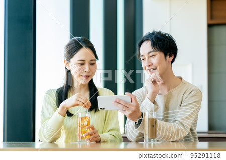 A young couple watching a video at a cafe A young couple watching a video at a cafe 95291118
