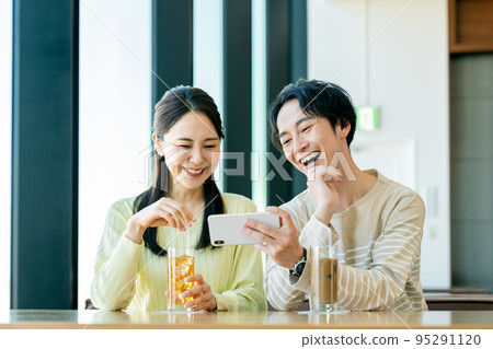 A young couple watching a video at a cafe A young couple watching a video at a cafe 95291120