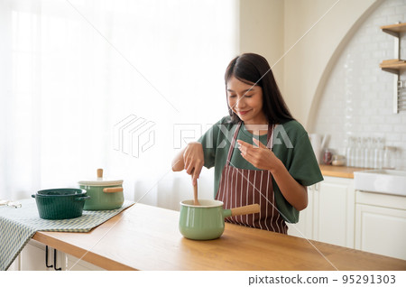 Young beauty asian woman cooking in kitchen room at home Young beauty asian woman cooking in kitchen room at home 95291303