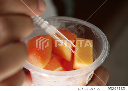 eating fresh papaya from a plastic container eating fresh papaya from a plastic container 95292185