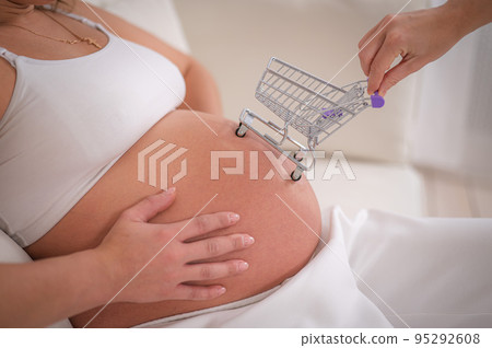 Faceless pregnant woman with shopping cart on her belly. Faceless pregnant woman with shopping cart on her belly. 95292608