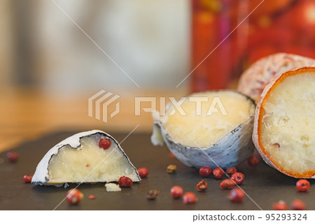 Belper knole with garlic and pink pepper in wood ash. Close-up view. Selective focus. Handmade cheese. 95293324