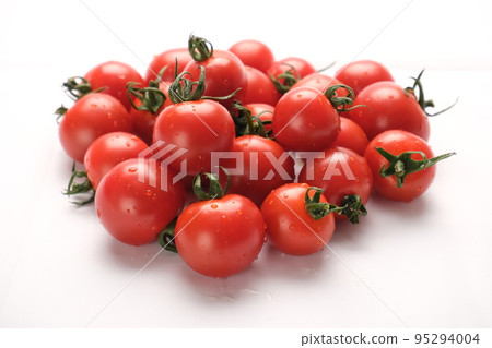 A large amount of mini tomatoes with water droplets are sparkling on a white background 95294004