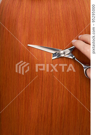 Hairdresser cuts long red hair with scissors Hairdresser cuts long red hair with scissors 95295000