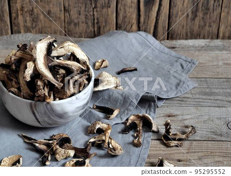 Dried champignon mushrooms in a bowl and on a cutting board. The idea of natural organic ecological products and their preparation for future use for autumn and winter. Dried champignon mushrooms in a bowl and on a cutting board. The idea of natural organic ecological products and their preparation for future use for autumn and winter. 95295552