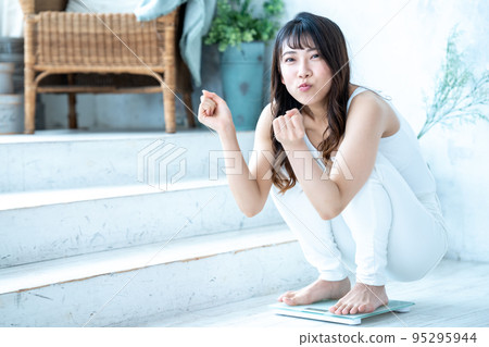 A young woman happy to measure her weight A young woman happy to measure her weight 95295944