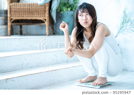 A young woman happy to measure her weight A young woman happy to measure her weight 95295947