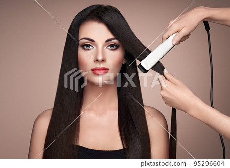 Hairdresser straightening long hair with hair irons Hairdresser straightening long hair with hair irons 95296604