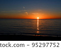 The sun on the horizon and the light trails reflected on the sea surface 95297752