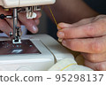 A woman's hand is sewing using an old sewing machine. 95298137
