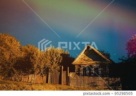 Night sky over house in old village. Night starry sky above house with bright stars and meteoric track trail. Glowing stars above summer nature Night sky over house in old village. Night starry sky above house with bright stars and meteoric track trail. Glowing stars above summer nature 95298505