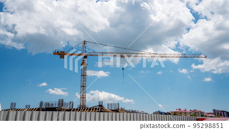 Construction of a building with a construction crane against the blue sky with plufy clouds background 95298851