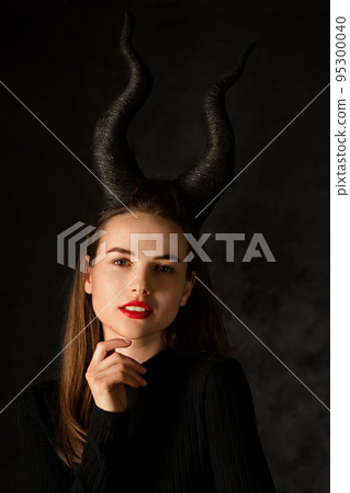 Young woman with long horns on a black background Young woman with long horns on a black background 95300040