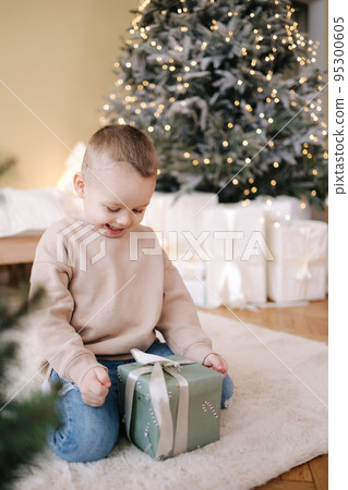 Cute little boy at home during winter holiday. Christmas tree and lot of presents Cute little boy at home during winter holiday. Christmas tree and lot of presents 95300605