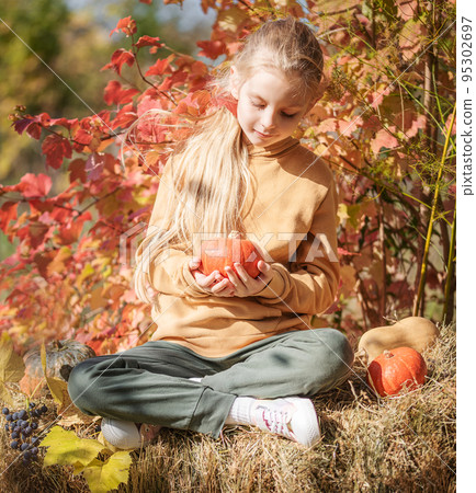 Girl in the hay with pumpkins Girl in the hay with pumpkins 95302697