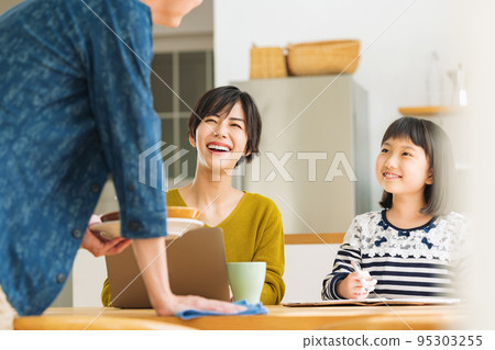 Mom and daughter talking to dad cleaning up the table Mom and daughter talking to dad cleaning up the table 95303255