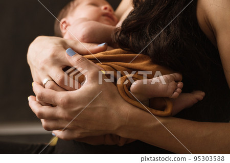 A mother holds her newborn son in her arms 95303588
