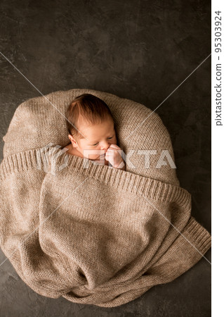 A newborn baby with a warm knitted blanket A newborn baby with a warm knitted blanket 95303924