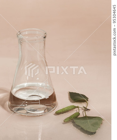Mockup of Glass flask on pink water surface. Science cosmetic laboratory concept. Cosmetology research, skin care products. 95304645