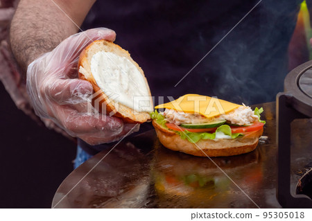 Chef preparing burger with fish at street food festival - close up Chef preparing burger with fish at street food festival - close up 95305018