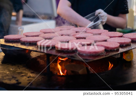 Chef grilling meat cutlets for burgers on brazier with hot flame Chef grilling meat cutlets for burgers on brazier with hot flame 95305041