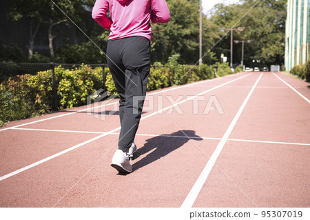 Back view of a middle-aged woman jogging Back view of a middle-aged woman jogging 95307019