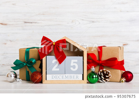 25 december. Christmas composition on colored background with a wooden calendar, with a gift box, toys, bauble copy space 95307675
