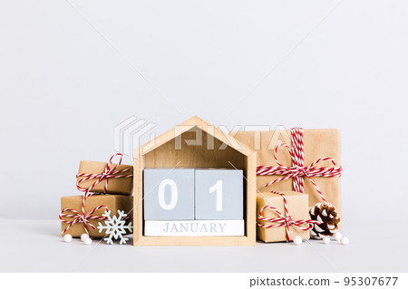 1 january. Christmas composition on colored background with a wooden calendar, with a gift box, toys, bauble copy space 1 january. Christmas composition on colored background with a wooden calendar, with a gift box, toys, bauble copy space 95307677