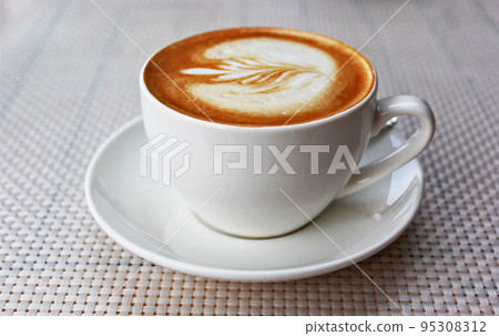 Hot art latte coffee in a cup on a white table Hot art latte coffee in a cup on a white table 95308312