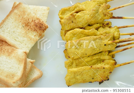 grilled pork satay couple bread dipping with sweet peanut sauce and pickled vegetable  Indonesian food on plate 95308551