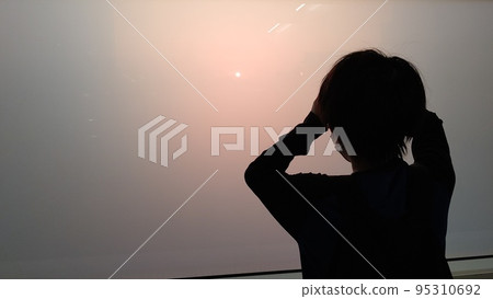 Boy looking at the sunset through frosted glass Boy looking at the sunset through frosted glass 95310692