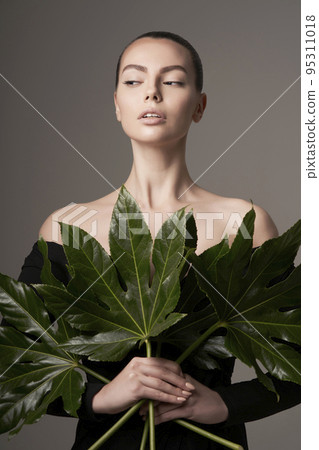 Portrait of a beautiful woman with grass leaves in her hands 95311018
