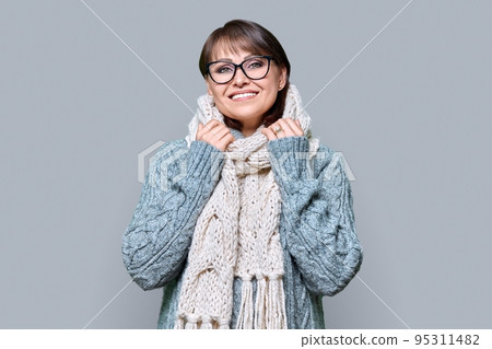 Winter portrait of mature woman in warm clothes on grey background 95311482