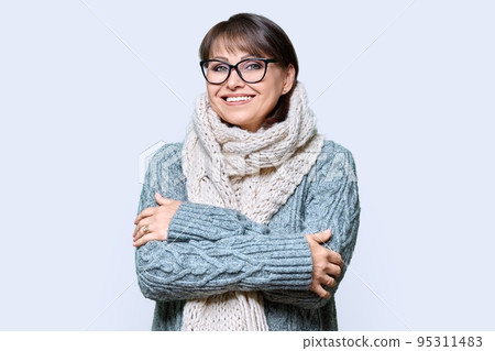 Winter portrait of mature woman in warm clothes on light background Winter portrait of mature woman in warm clothes on light background 95311483