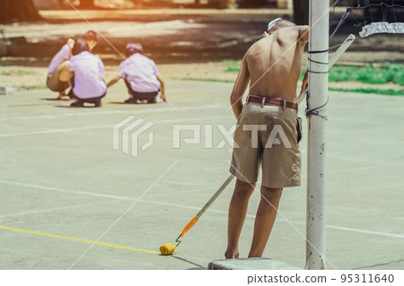 Male students use small paint rollers to paint yellow lines on the cement floor for Sepak Takraw training. 95311640