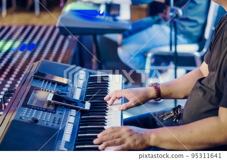 Musician play electronic keyboard synthesizers by using smartphone as guidelines for playing on the concert stage. Selective focus on smartphone. Musician play electronic keyboard synthesizers by using smartphone as guidelines for playing on the concert stage. Selective focus on smartphone. 95311641