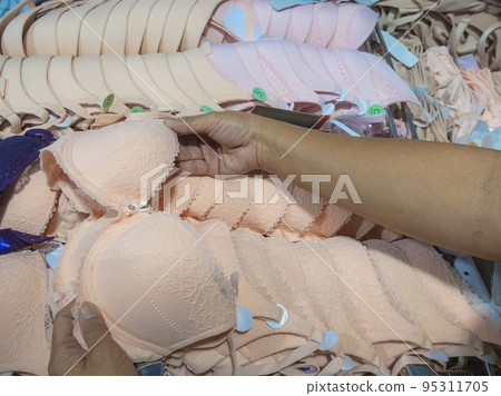 Hands of mature woman choosing or searching new brassiere cups size in underwear shop. Woman customer shopping bra. Female deciding at lingerie shop department store. Different sizes of underwear. 95311705