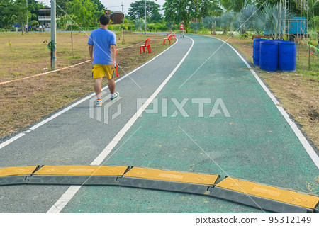 Black and yellow heavy plastic covers for people and vehicle to cross over cables laid on road. Pavement pads to protect electrical wiring on sidewalk in public park. Channel for laying the wires. 95312149
